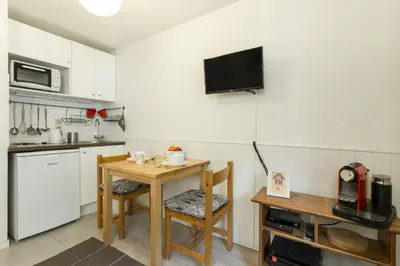 a kitchen with a table and a tv on the wall at Apartment Blanc Neige 2 - Centre de Chamonix in Chamonix-Mont-Blanc