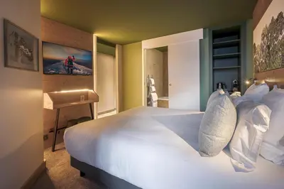 a bedroom with a white bed and a desk at Lykke Hôtel & Spa Chamonix - ex Mercure in Chamonix-Mont-Blanc