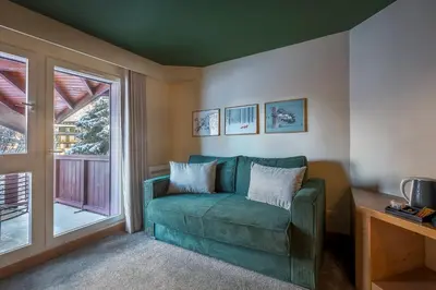 a living room with a green couch and a window at Lykke Hôtel & Spa Chamonix - ex Mercure in Chamonix-Mont-Blanc