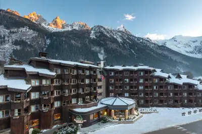 a hotel with snow covered mountains in the background at Lykke Hôtel & Spa Chamonix - ex Mercure in Chamonix-Mont-Blanc