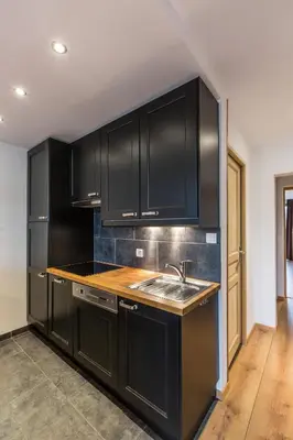 a kitchen with black cabinets and a sink at Apartment Periades - Central Chamonix Incredible Mountain Views in Chamonix-Mont-Blanc