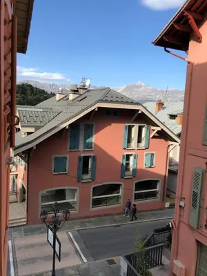 a red building with people walking down a street at Le Studio Alpin - Hyper centre Saint Gervais in Saint-Gervais-les-Bains