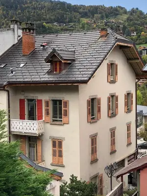 a white house with red doors and windows at Le Studio Alpin - Hyper centre Saint Gervais in Saint-Gervais-les-Bains