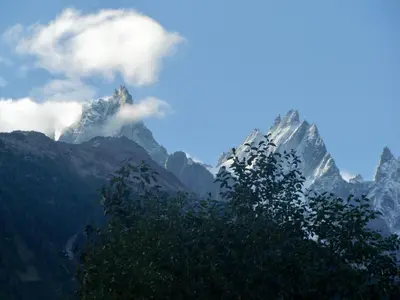 a view of a mountain range with clouds and trees at Chalet Les Lupins in Chamonix-Mont-Blanc