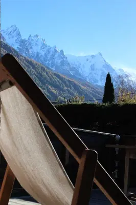 a chair on a balcony with a view of mountains at Chalet Les Lupins in Chamonix-Mont-Blanc