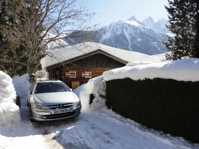 a car parked in front of a house covered in snow at Chalet Les Lupins in Chamonix-Mont-Blanc