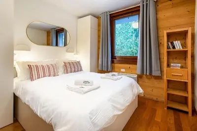 a bedroom with a large white bed with a mirror at Le Paradis 15 Apartment - Chamonix All Year in Chamonix-Mont-Blanc