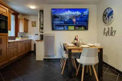 a kitchen with a table and a television on the wall at Le Paradis 15 Apartment - Chamonix All Year in Chamonix-Mont-Blanc