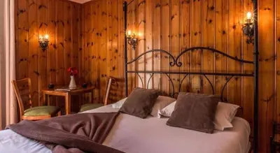 a bedroom with a bed with wooden walls and wood floors at Hotel Le Chamonix in Chamonix-Mont-Blanc