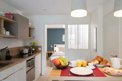 a kitchen with a table with fruits and drinks on it at Le Génépy - Appart'hôtel de Charme in Chamonix-Mont-Blanc