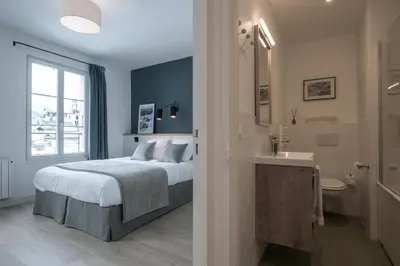 a bedroom with a bed and a bathroom with a sink at Le Génépy - Appart'hôtel de Charme in Chamonix-Mont-Blanc