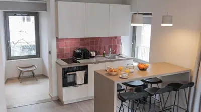 a kitchen with a counter and stools in it at Le Génépy - Appart'hôtel de Charme in Chamonix-Mont-Blanc