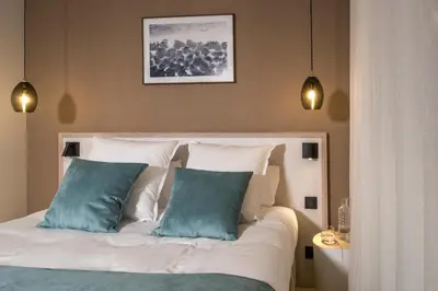 a bedroom with a bed with two blue pillows at Le Génépy - Appart'hôtel de Charme in Chamonix-Mont-Blanc