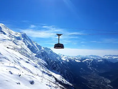 a ski lift flying over a snow covered mountain at Le Chamois 5E Balcon panoramique MontBlanc avec parking gratuit in Chamonix-Mont-Blanc
