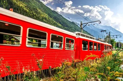 a red and white train with mountains in the background at Le Chamois 5E Balcon panoramique MontBlanc avec parking gratuit in Chamonix-Mont-Blanc