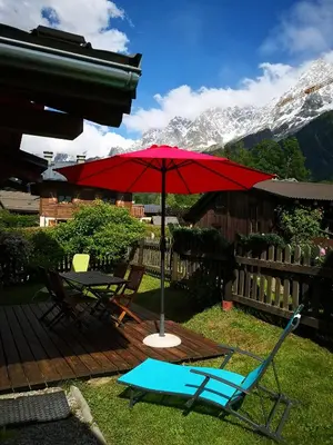 a red umbrella sitting on a deck with a table and chairs at Les Chalets du Bonheur in Les Houches