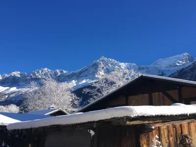 a cabin with snow covered mountains in the background at Les Chalets du Bonheur in Les Houches