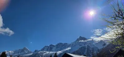 a view of a mountain range with the sun in the sky at Les Chalets du Bonheur in Les Houches