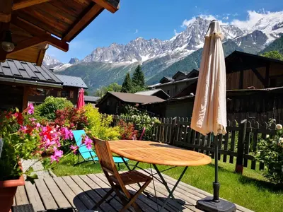a table and chairs and an umbrella on a deck at Les Chalets du Bonheur in Les Houches