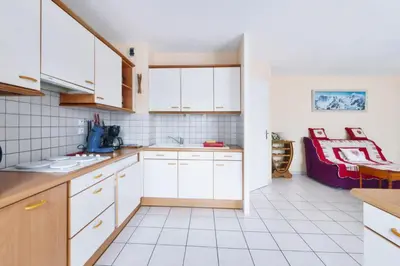 a kitchen with white cabinets and a couch in the background at Appartement Very - Welkeys in Sallanches