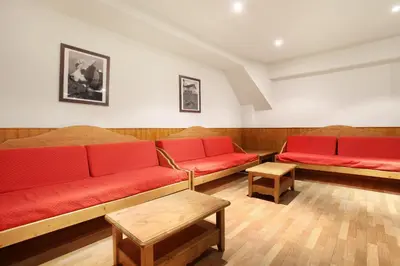 a living room with two red couches and tables at Résidence Odalys Le Front de Neige in Les Carroz d'Araches