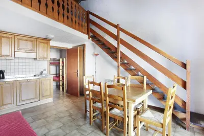 a kitchen and dining room with a table and a staircase at Résidence Odalys Le Front de Neige in Les Carroz d'Araches