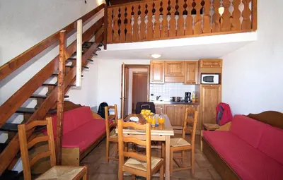 a kitchen and dining room with a table and a staircase at Résidence Odalys Le Front de Neige in Les Carroz d'Araches
