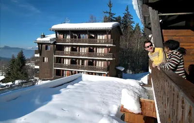 two people standing on a balcony in the snow at Résidence Odalys Le Front de Neige in Les Carroz d'Araches
