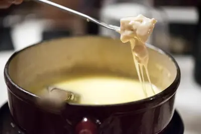 a person stirring a pot of soup with a spoon at Chalet-Hôtel La Chemenaz in Les Contamines-Montjoie