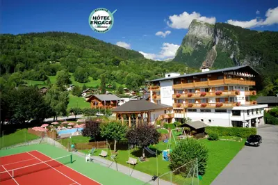 a hotel with a tennis court in front of a mountain at Chalet-Hôtel Neige et Roc, The Originals Relais in Samoëns