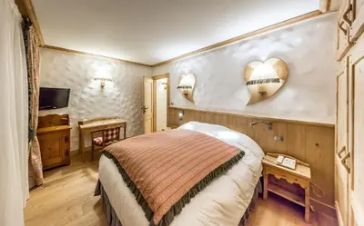 a bedroom with a bed and a mirror on the wall at Chalet-Hôtel Neige et Roc, The Originals Relais in Samoëns