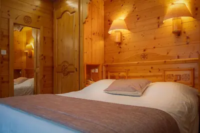 a bedroom with a bed in a wooden room at Chalet-Hôtel Neige et Roc, The Originals Relais in Samoëns