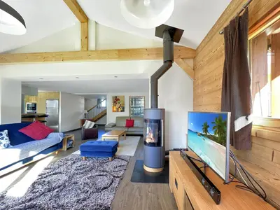 a living room with a blue couch and a tv at Chalet Haut Standing à proximité du centre (CH228) in Les Carroz d'Araches