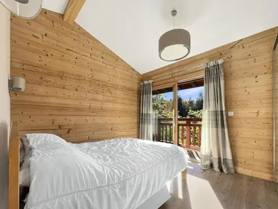 a bedroom with a wooden wall with a bed and a window at Chalet Haut Standing à proximité du centre (CH228) in Les Carroz d'Araches