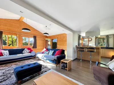a living room with two couches and a kitchen at Chalet Haut Standing à proximité du centre (CH228) in Les Carroz d'Araches