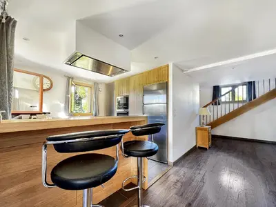 a kitchen with two bar stools in front of a counter at Chalet Haut Standing à proximité du centre (CH228) in Les Carroz d'Araches