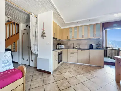 a kitchen with wooden cabinets and a large window at Duplex 6/8 Pers Télécabine des Carroz (ES116) in Les Carroz d'Araches