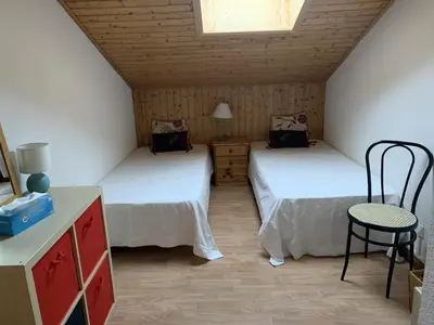 a room with two beds and a table and a chair at Duplex 6/8 Pers Télécabine des Carroz (ES116) in Les Carroz d'Araches