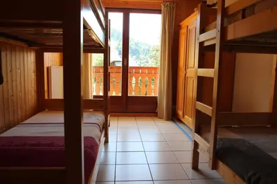 a room with two bunk beds and a window at 2 Pièces 6 Pers centre station (GV211) in Les Carroz d'Araches
