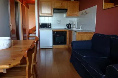a kitchen with a wooden table and a blue couch at Duplex 6 Pers centre station Carroz (SA315) in Les Carroz d'Araches