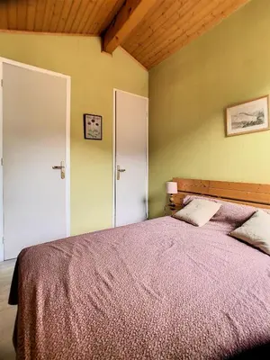 a bedroom with a large bed and two white doors at Duplex 8 Pers centre des Carroz (SL404) in Les Carroz d'Araches