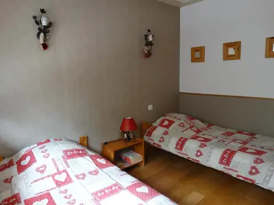 a bedroom with two beds and a table with a lamp at Appartement cosy à Samoëns avec jacuzzi in Samoëns