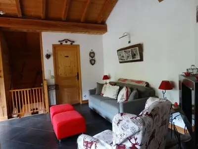a living room with a couch and a red stool at Appartement cosy à Samoëns avec jacuzzi in Samoëns