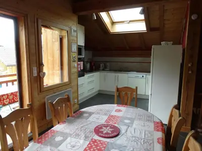 a kitchen with a table and a white refrigerator at Appartement cosy à Samoëns avec jacuzzi in Samoëns