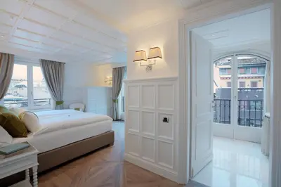 a white bedroom with a bed and a window at Grand Hôtel des Alpes in Chamonix-Mont-Blanc
