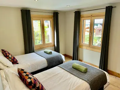 two beds in a room with two windows at The Castle, 10 Bedroom Chalet, Chamonix Centre in Chamonix-Mont-Blanc