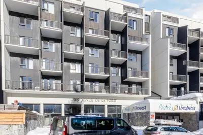 a large apartment building with cars parked in front of it at Residence La Foret - maeva Home in Arâches-la-Frasse