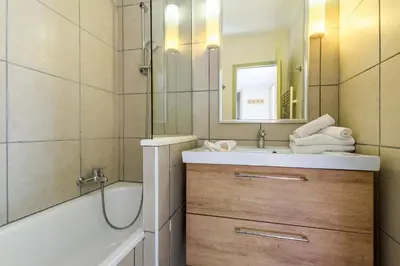 a bathroom with a sink and a tub and a mirror at Residence La Foret - maeva Home in Arâches-la-Frasse