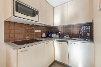 a kitchen with white cabinets and a microwave at Residence La Foret - maeva Home in Arâches-la-Frasse