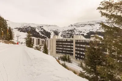 a snow covered slope in front of a building at Residence La Foret - maeva Home in Arâches-la-Frasse